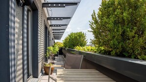 A rooftop terrace with a pergola, seating area, and potted plants. - Hotel NEWBERLIN (Berlin)