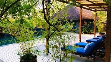 Una piscina al aire libre, sombrillas, sillones reclinables de piscina