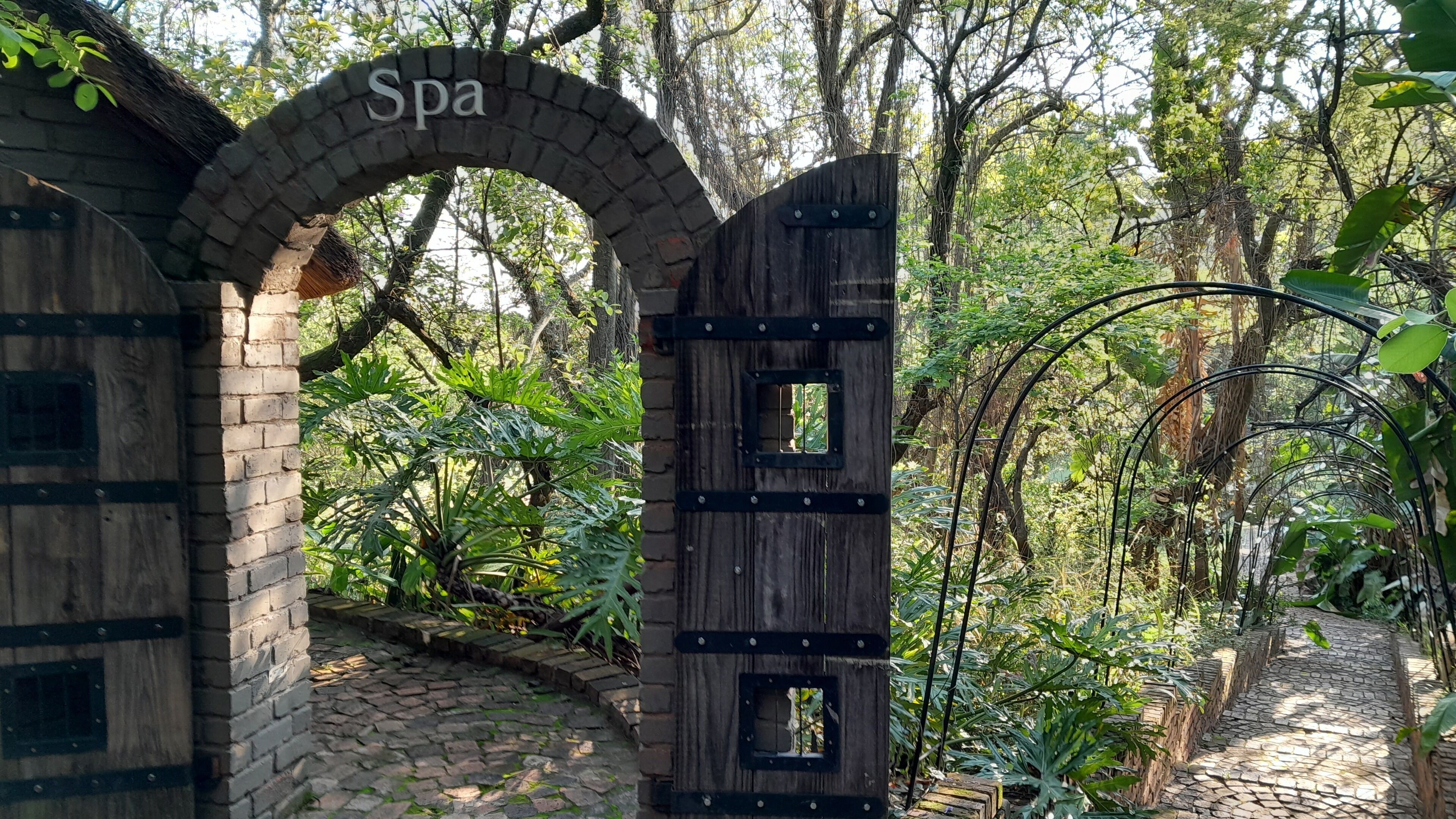 An arched entrance labeled "Spa" with a rustic wooden door and a brick wall.