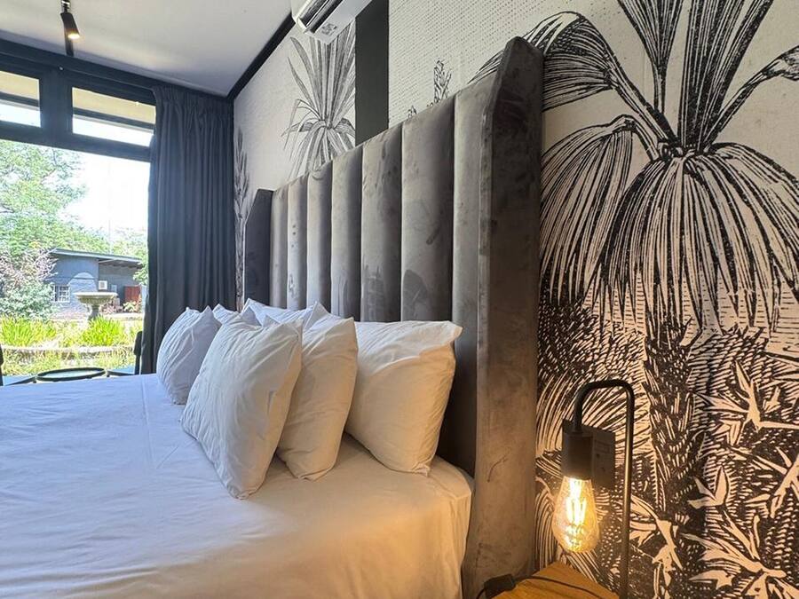 Ein modernes Schlafzimmer mit einem großen Bett, einem Holznachttisch, einer Wand-Klimaanlage und einer dekorativen Leuchte.
