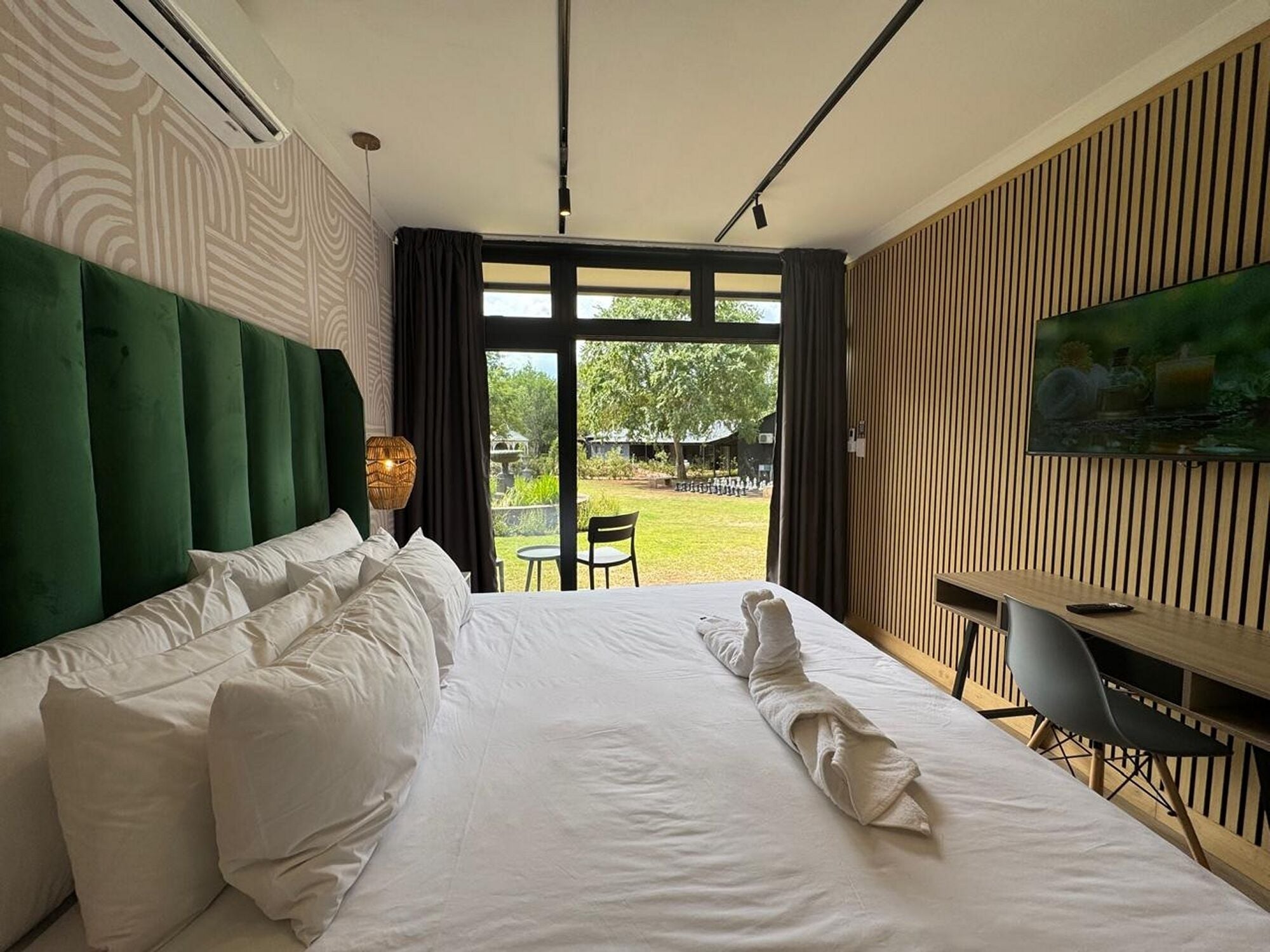 A hotel room with a large bed, a desk, and a TV.