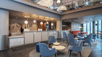 Un vestíbulo moderno con mostrador de recepción, zona de estar y bar.