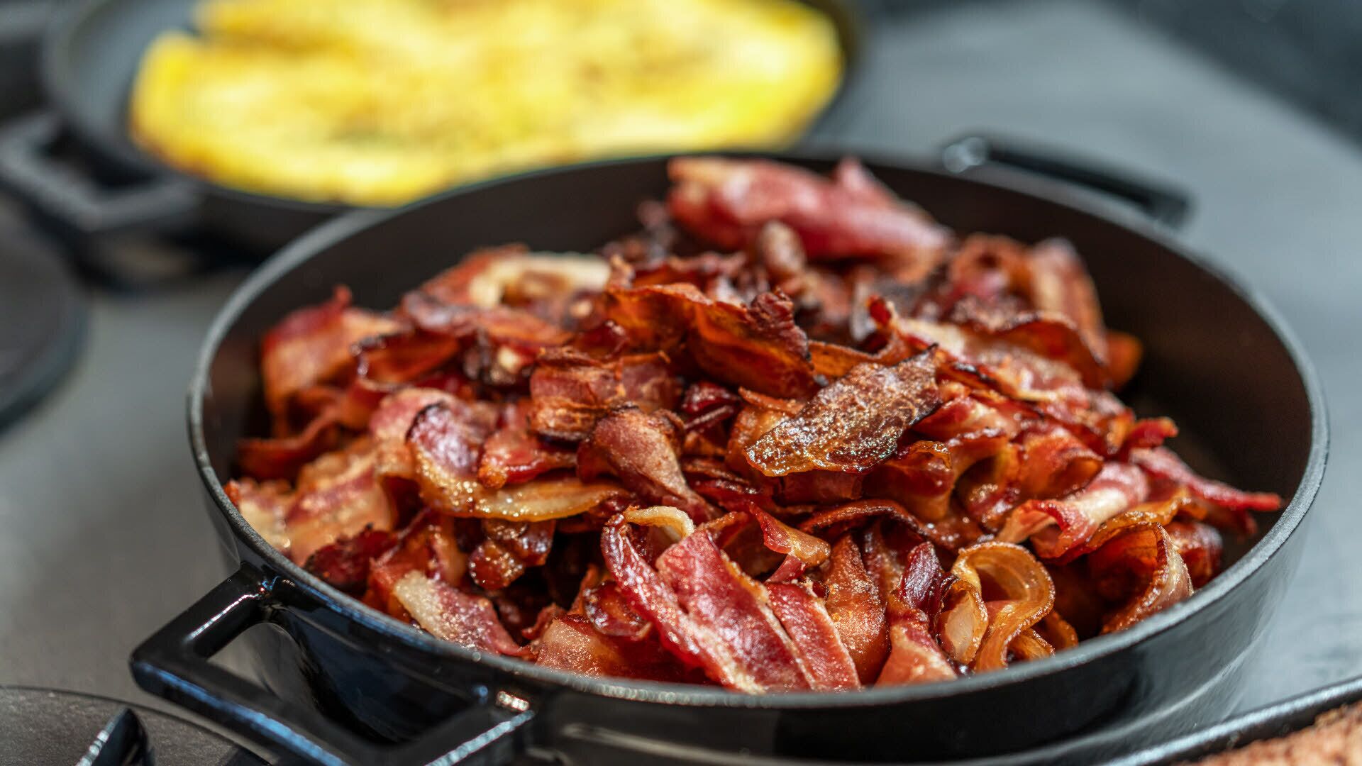 Uma frigideira com tiras de bacon cozido.