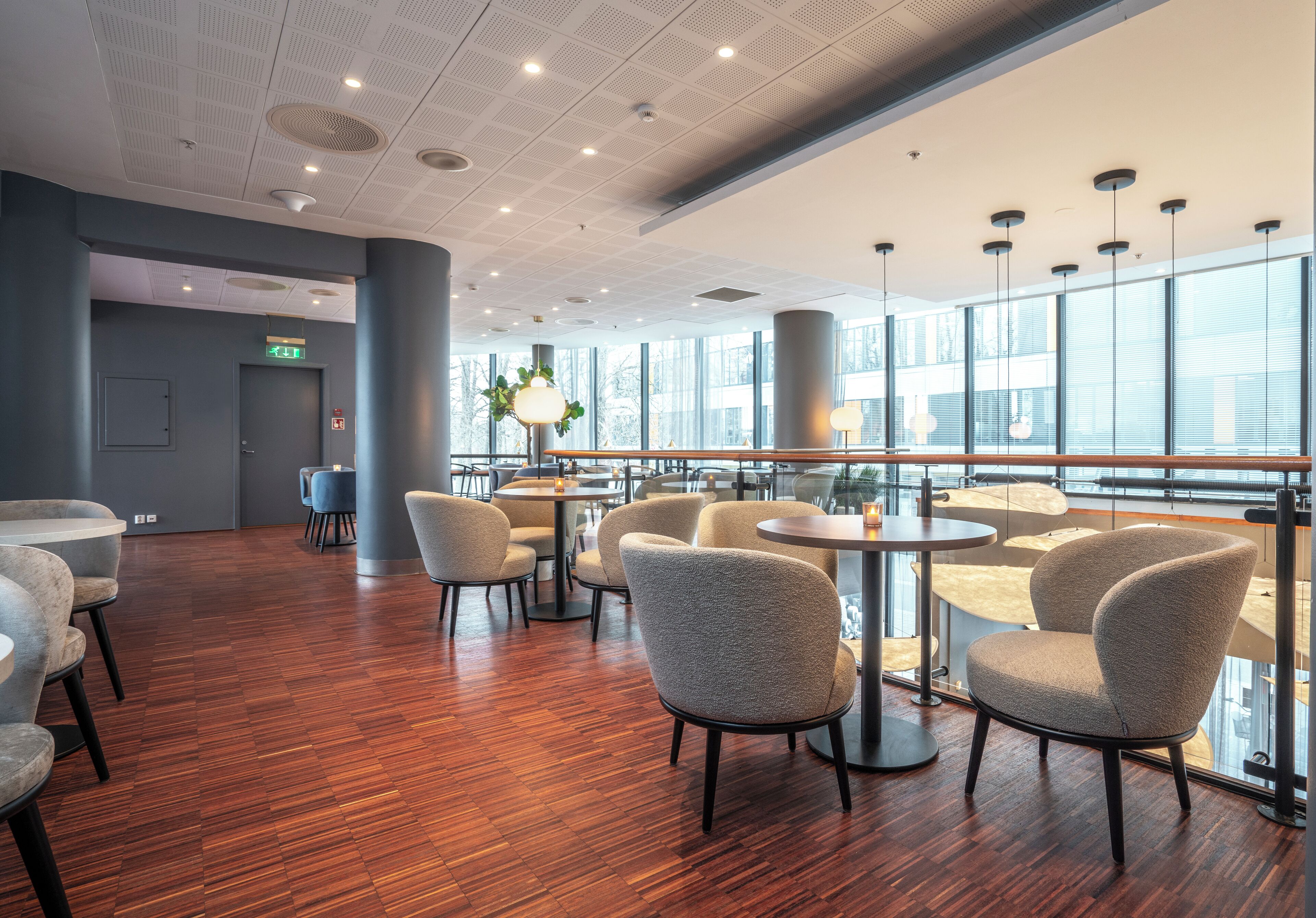A modern interior with wooden flooring, round tables, and upholstered chairs.
