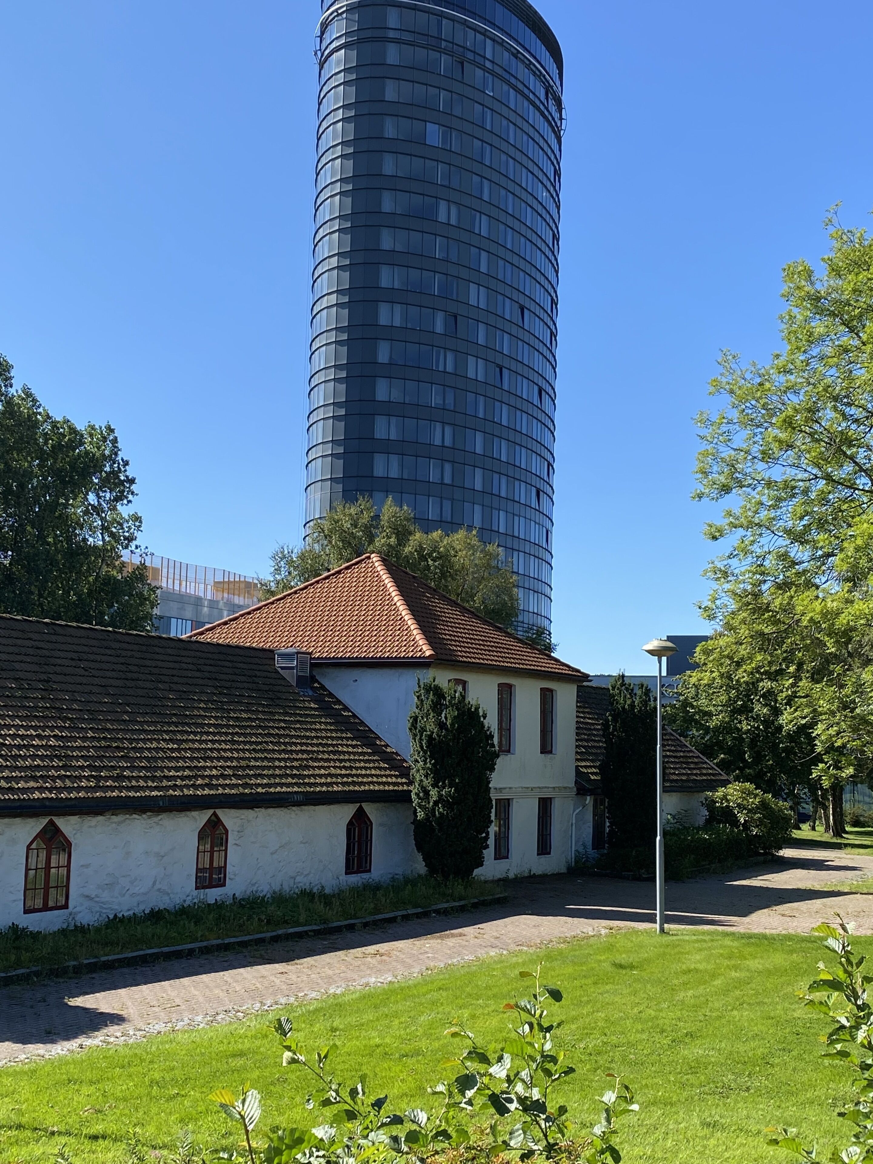 A traditional building with a tiled roof and a modern cylindrical structure in the background.