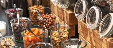 A buffet with various food items in glass containers, including nuts, dried fruits, and granola.