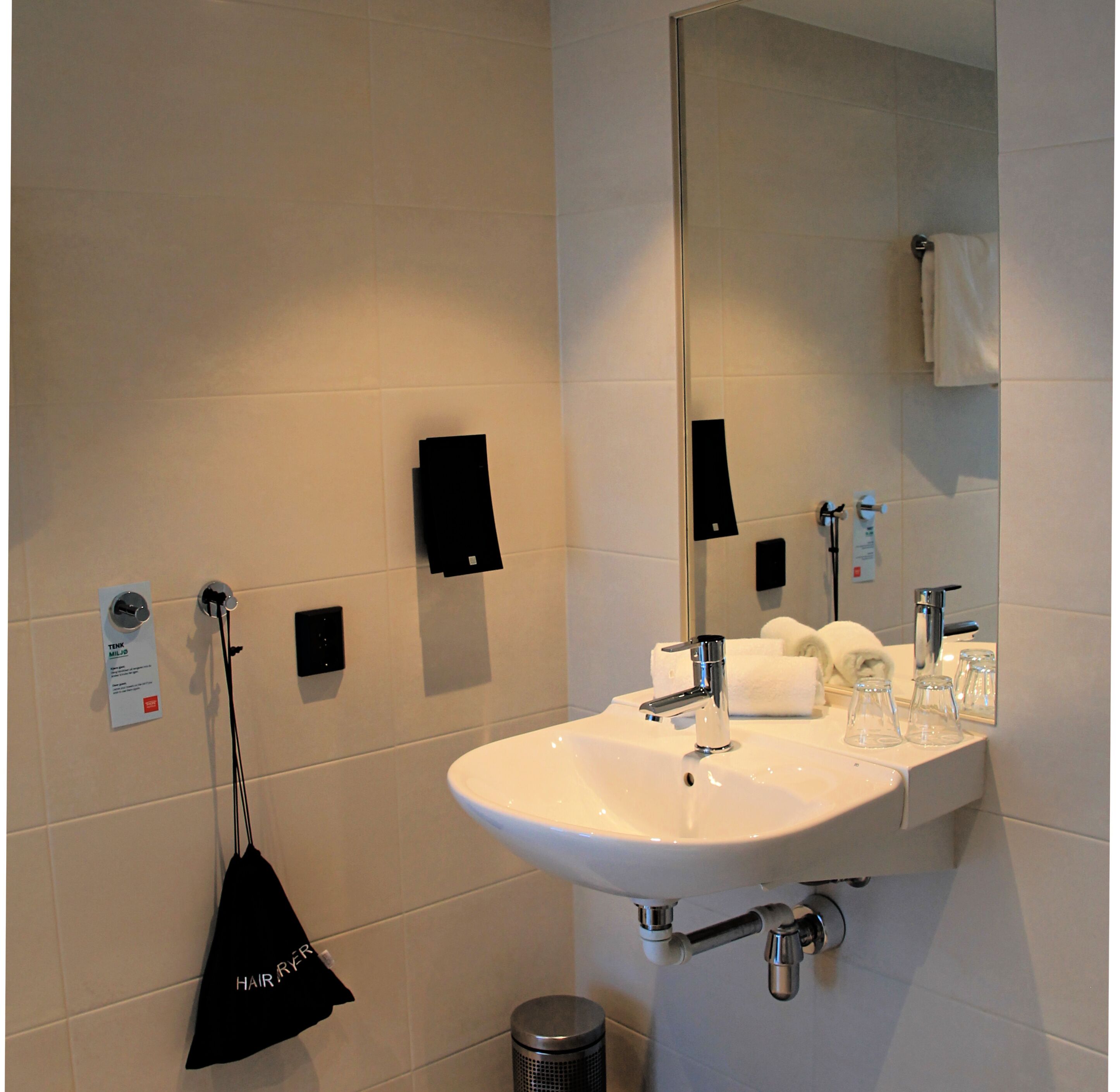 A modern bathroom with a white sink, mirror, and towel rack.
