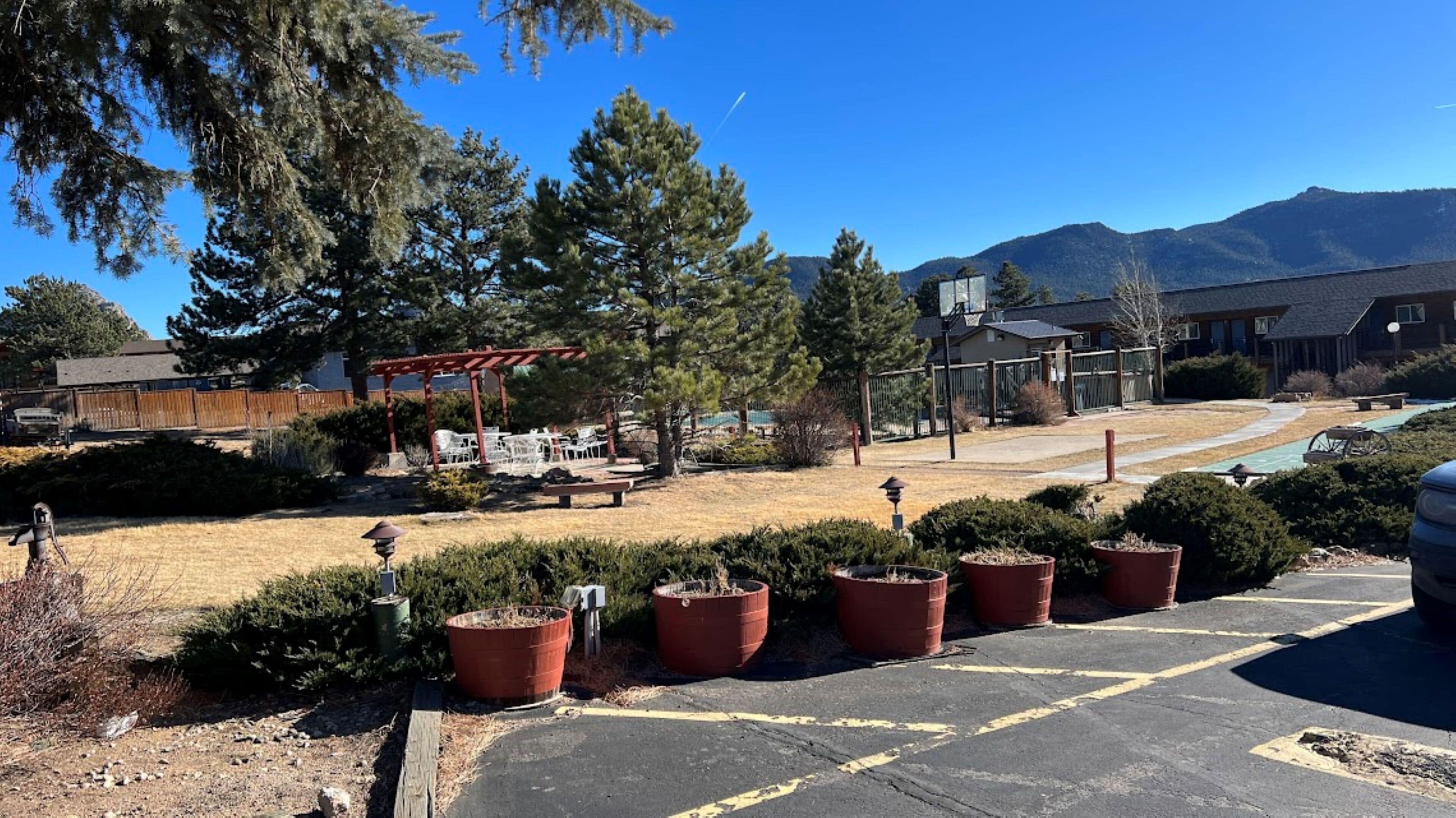 A parking lot with a red pergola, potted plants, and a view of mountains.