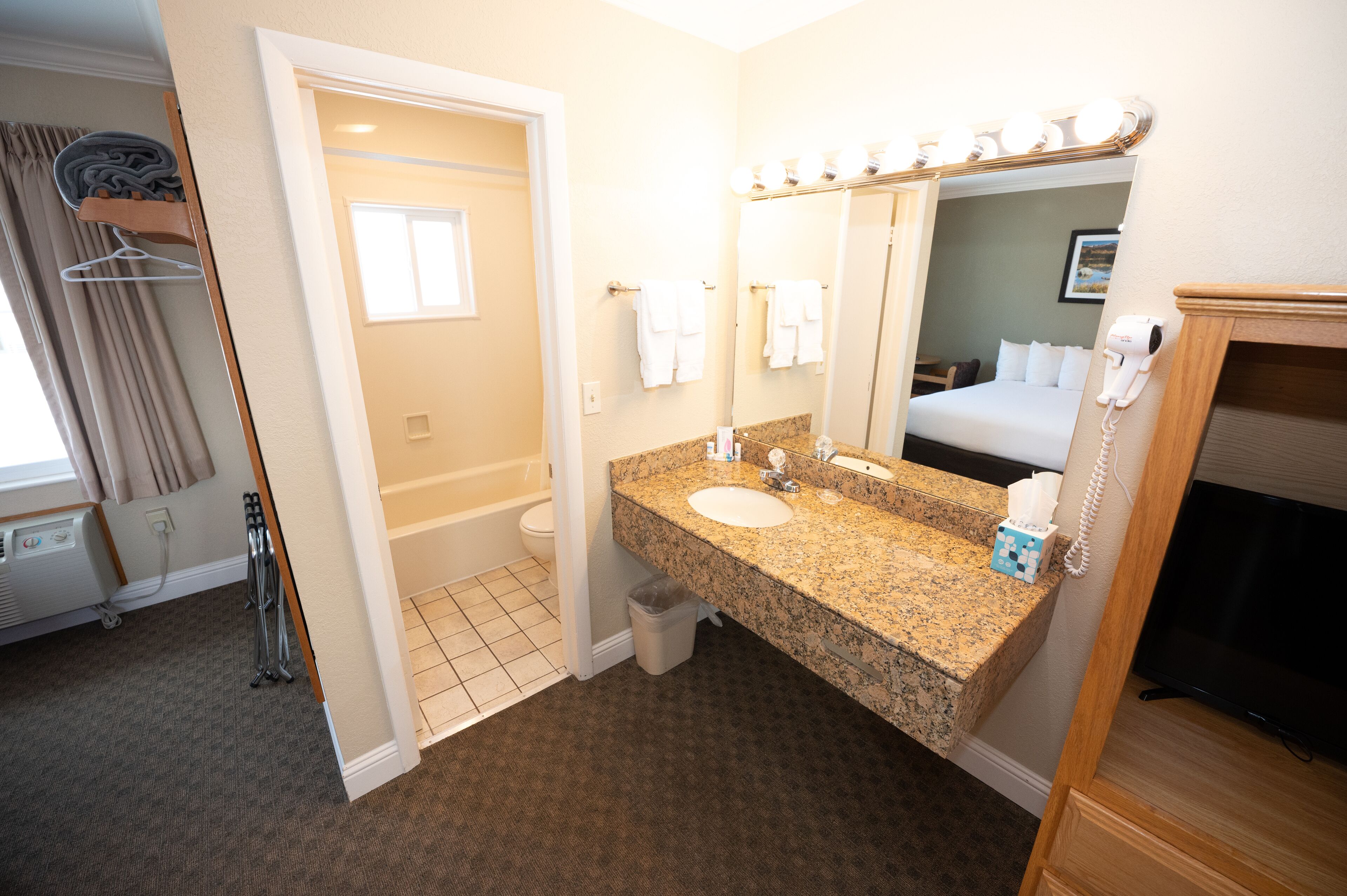 A hotel bathroom with a sink, mirror, and vanity.