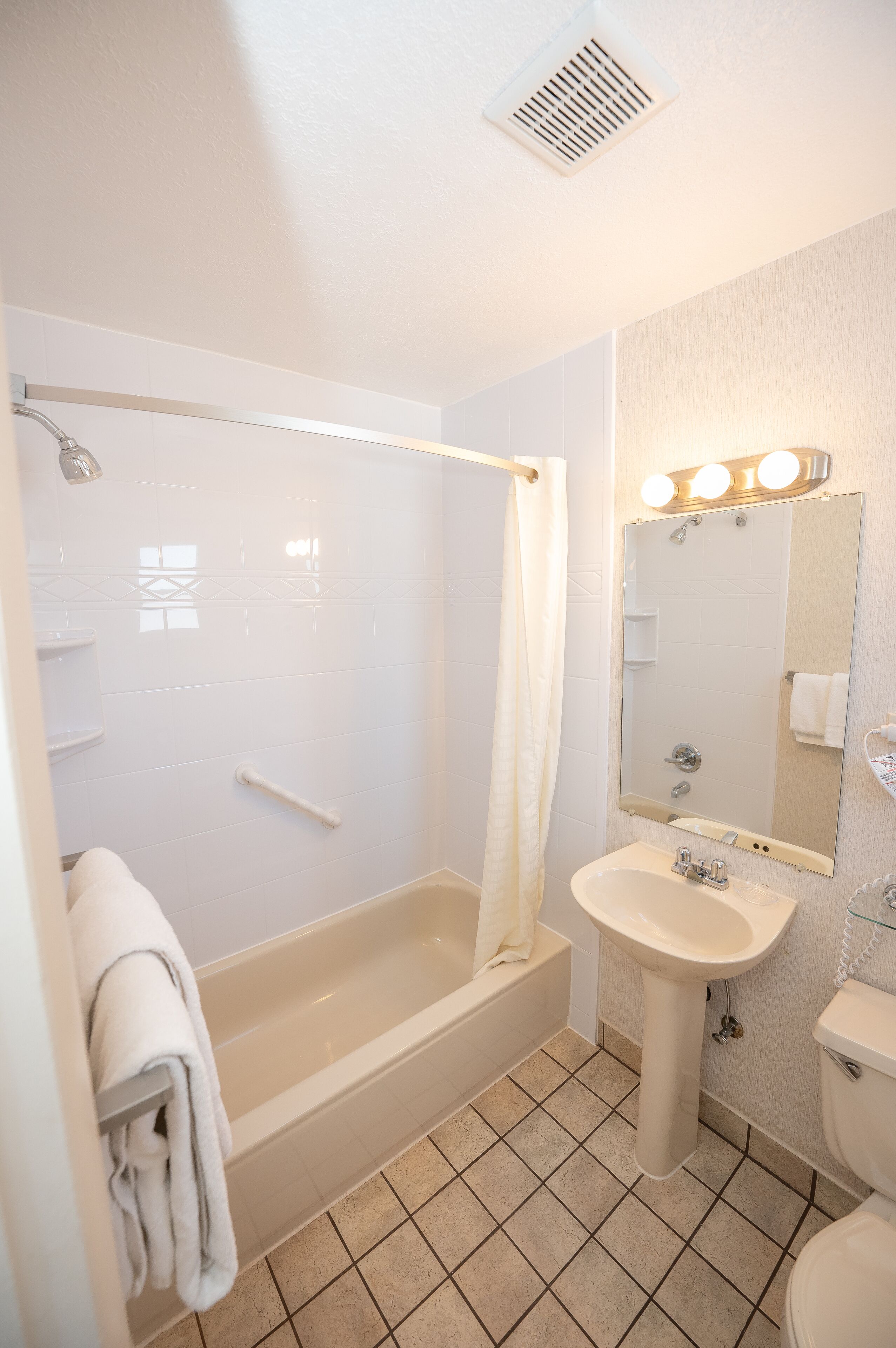 Ein Badezimmer mit Badewanne, Waschbecken, Toilette und einem beleuchteten Spiegel.