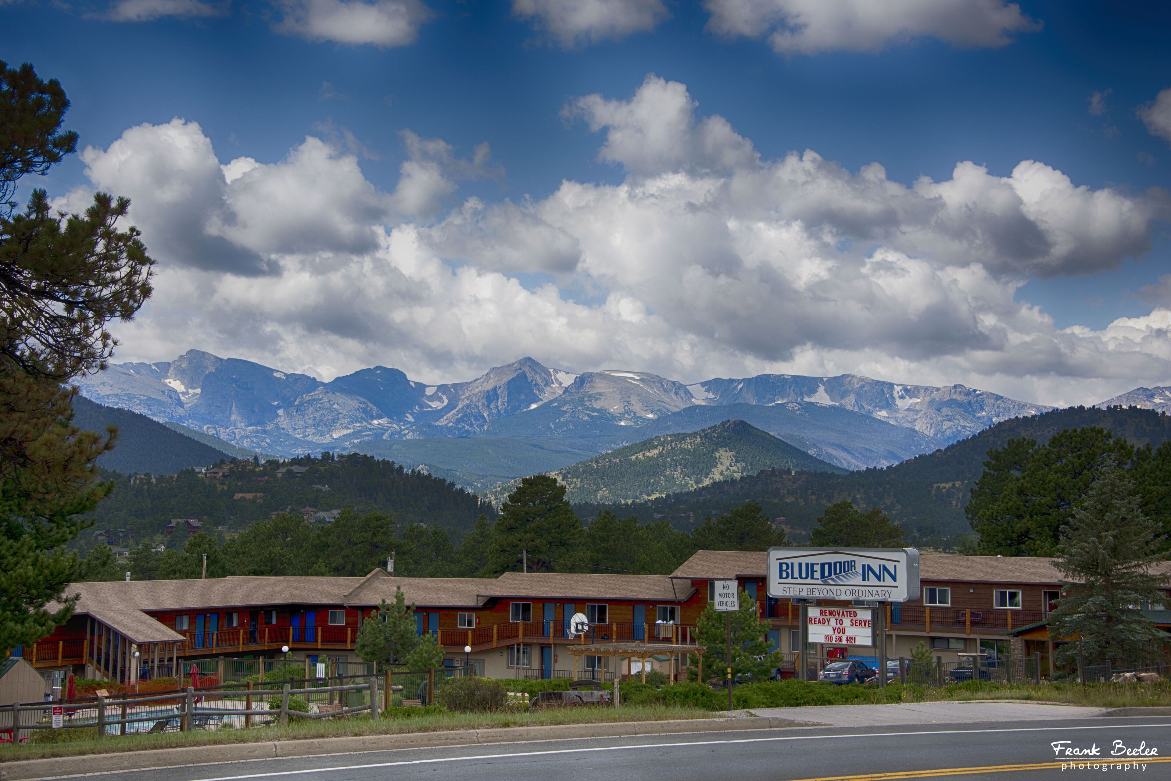 Un motel con montañas al fondo, un cartel y cielo despejado.