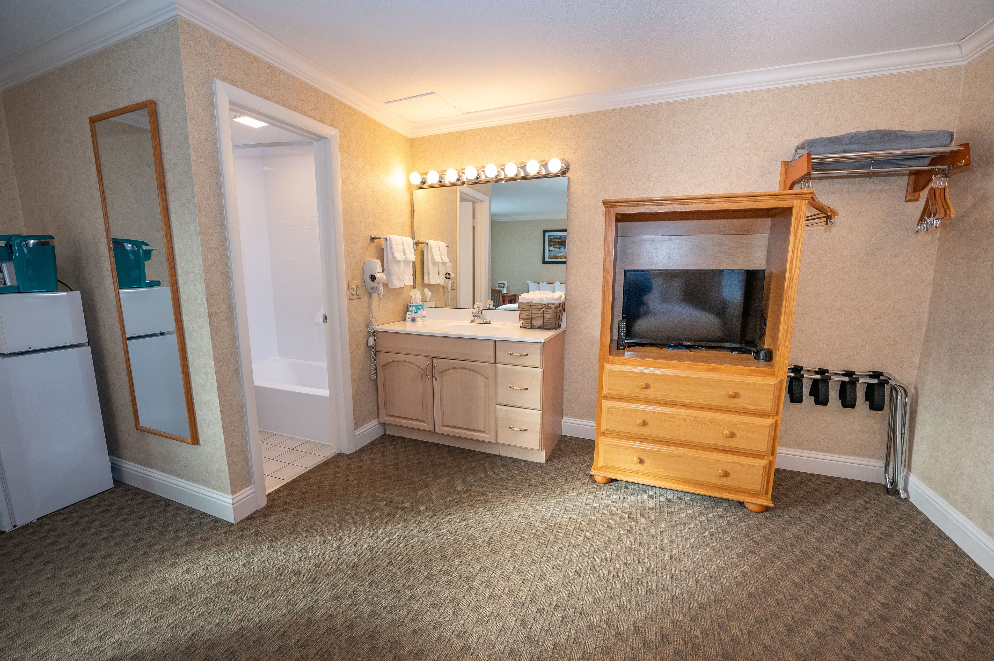 Ein Hotelbad mit Waschbecken, Spiegel, Schminktisch und einem Holzschrank.