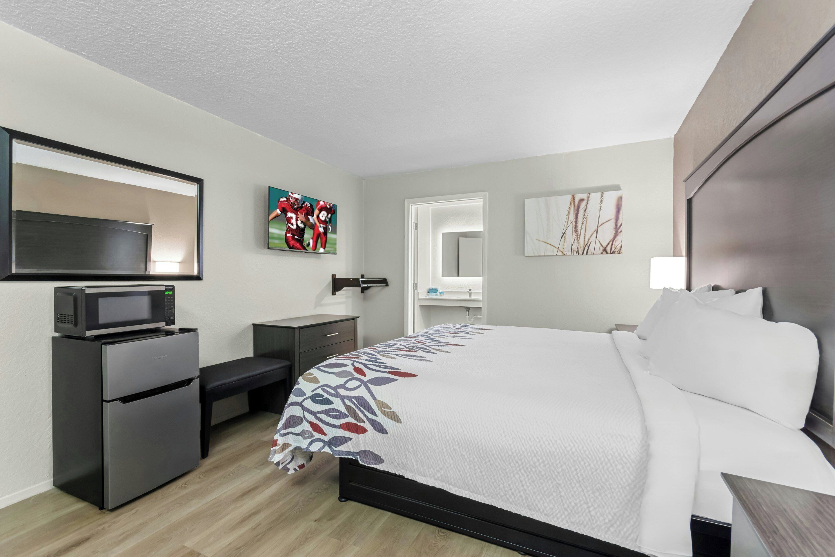 Une chambre d’hôtel comprenant un lit, un bureau avec un micro-ondes, une commode et un miroir.