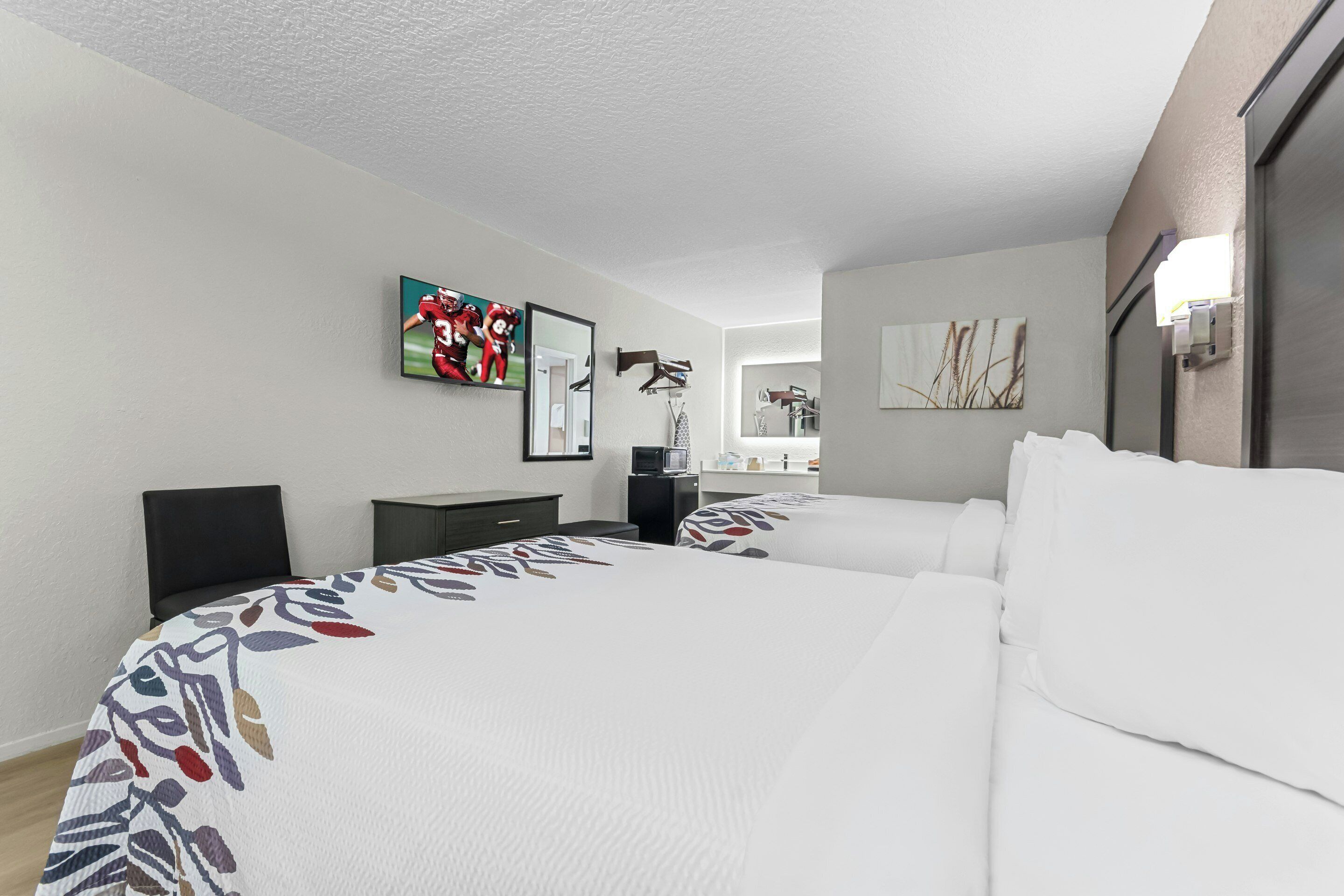 Habitació d'hotel amb dos llits, una televisió, una taula i un mirall.