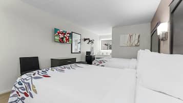 A hotel room with two beds, a TV, a desk, and a mirror.