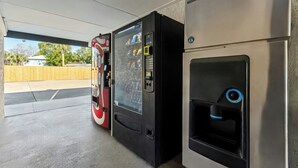 Una máquina expendedora y un dispensador de agua en un espacio exterior cubierto.
