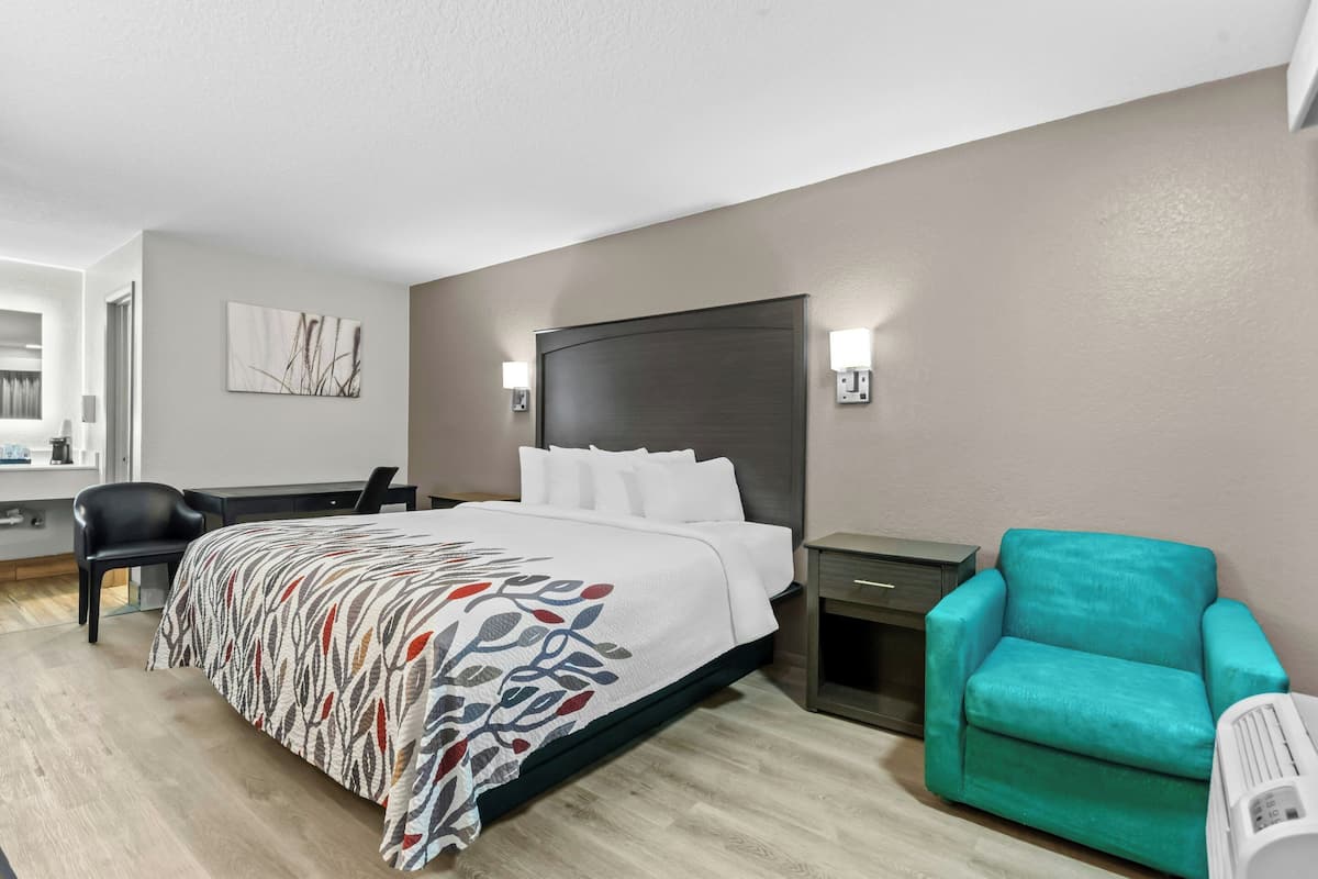 Ein Hotelzimmer mit Bett, Schreibtisch, Stuhl und kleinem Tisch.