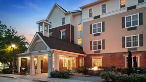 A multi-story hotel with a covered entrance, outdoor seating area, and a well-lit lobby. - TownePlace Suites by Marriott Chicago Lombard (Lombard)