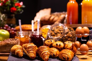 A breakfast spread with croissants, bread, eggs, and fruit.