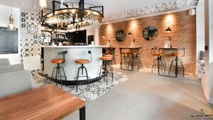 Uma área de bar moderna com balcão central, banquetes e piso estampado.