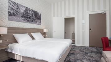 Een hotelkamer met een groot bed, een hoofdeinde, een nachtkastje, een rode stoel en een deur naar een badkamer.