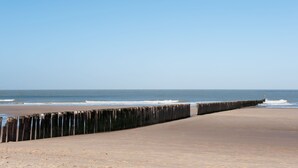 A beach with a wooden walkway leading to the water.
