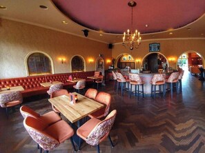 Ein Restaurant mit Sitzecken, runden Tischen und einer Bar.