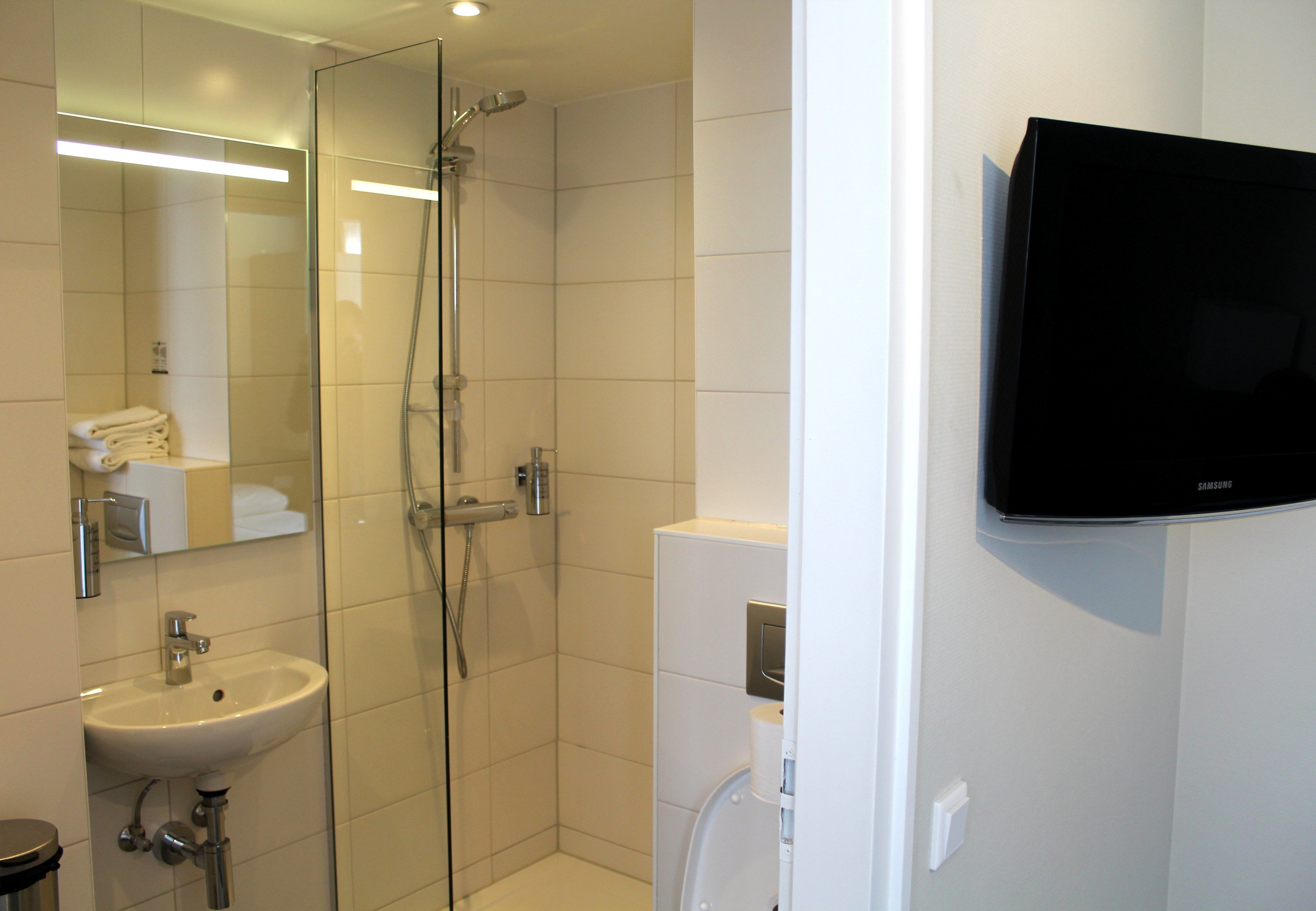 Un baño moderno con cabina de ducha de vidrio, un lavamanos y un inodoro.