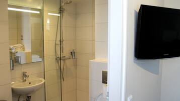 Un baño moderno con cabina de ducha de vidrio, un lavamanos y un inodoro.