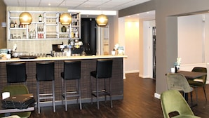 A bar area with a counter, stools, and a variety of bottles and glasses. - Fletcher Hotel Valkenburg (Valkenburg aan de Geul)