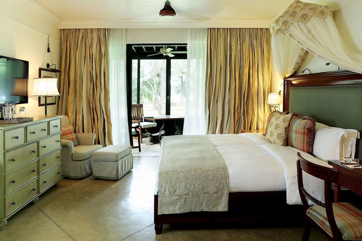 A hotel room with a bed, a desk, a chair, a dresser, and a television.