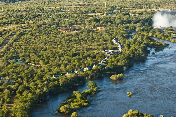 An aerial view of a river with a row of houses along its banks. - Royal Livingstone Victoria Falls Zambia Hotel by Anantara (Livingstone)