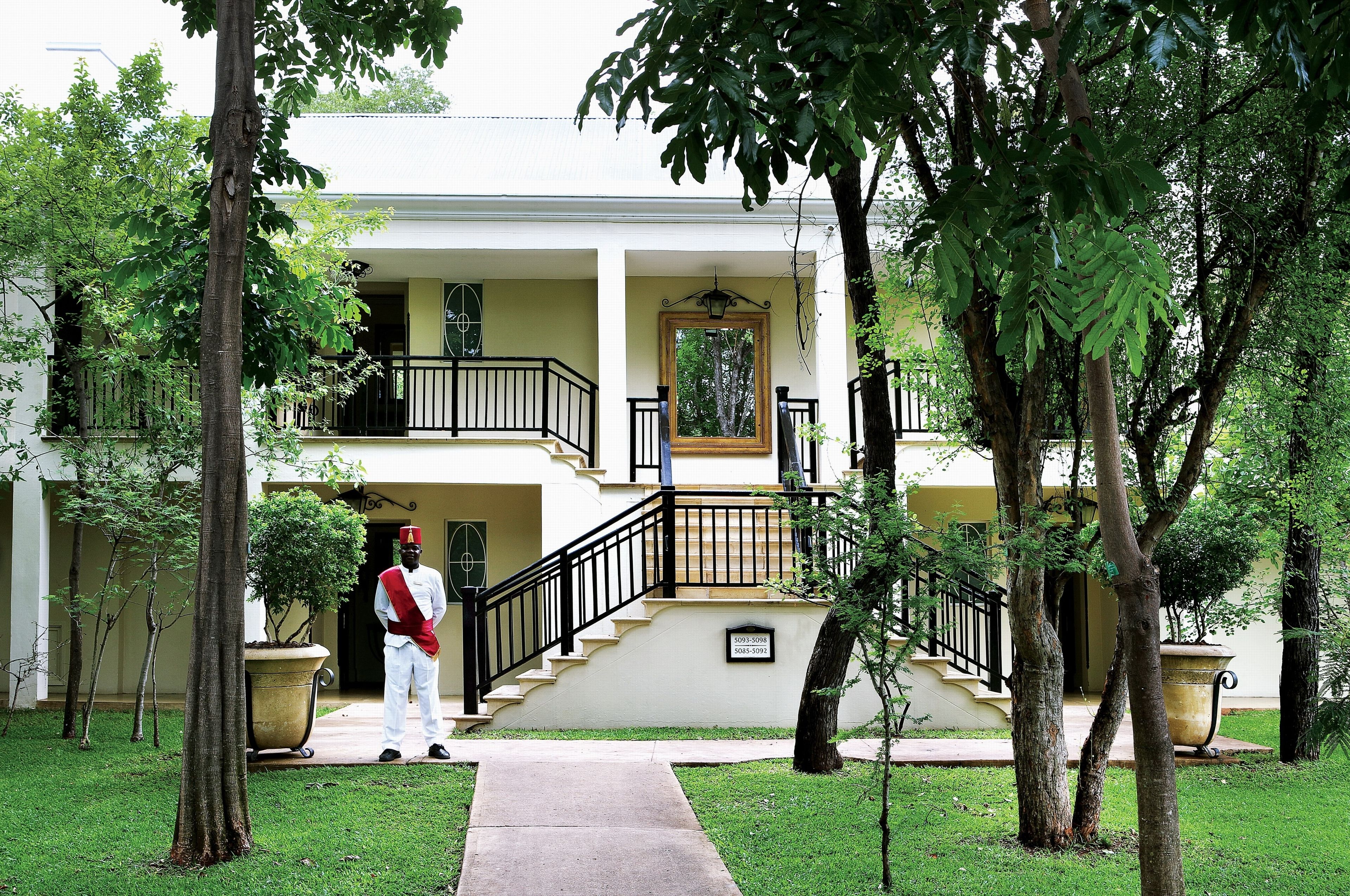 A two-story building with a central staircase, a large planter, and a uniformed staff member.