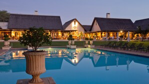 A resort with a large pool, thatched-roof buildings, and outdoor seating areas. - Royal Livingstone Victoria Falls Zambia Hotel by Anantara (Livingstone)