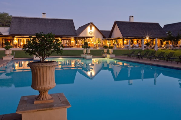 A resort with a large pool, thatched-roof buildings, and outdoor seating areas. - Royal Livingstone Victoria Falls Zambia Hotel by Anantara (Livingstone)