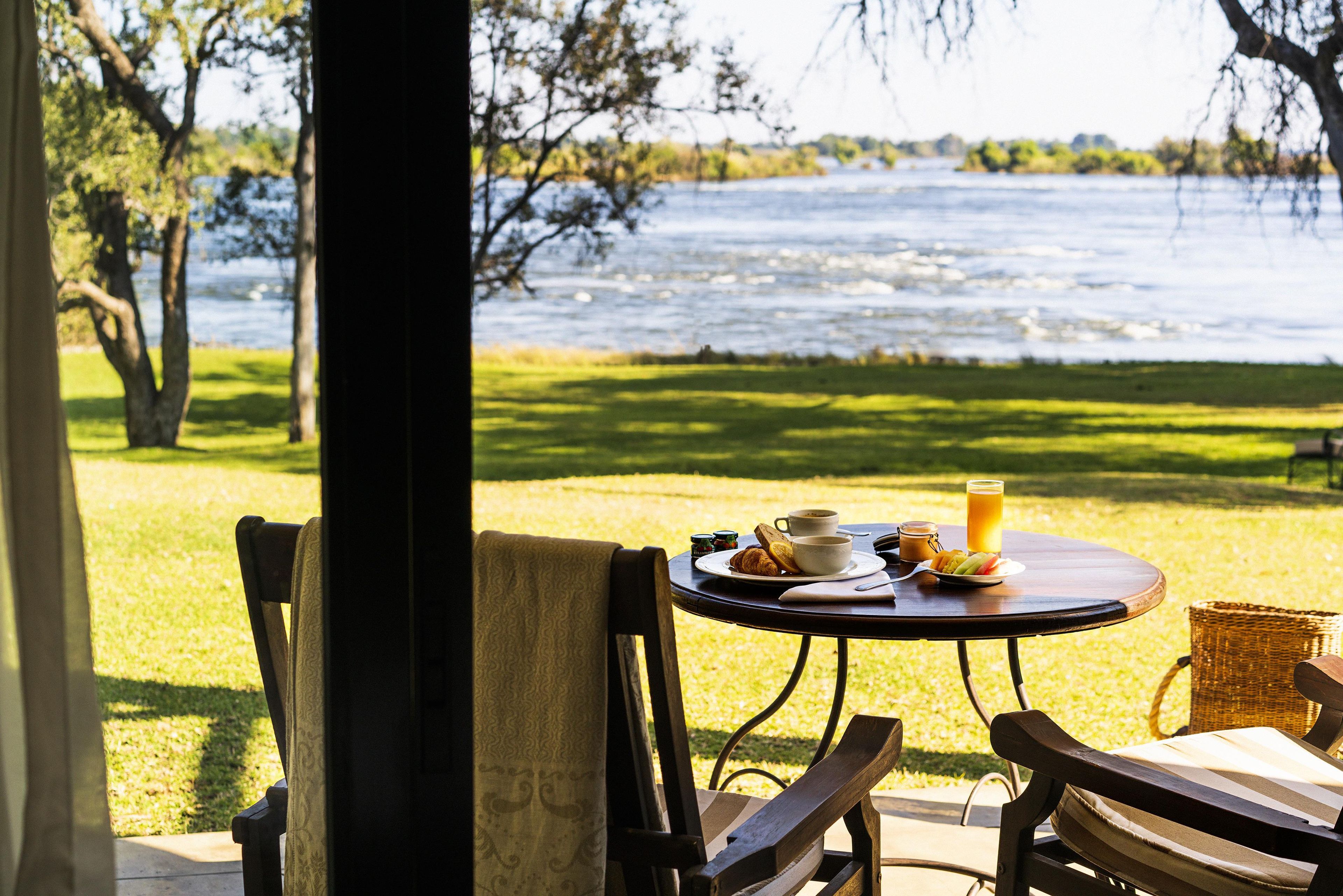 Une table dressée avec des aliments pour le petit-déjeuner, donnant sur un lac.