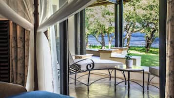 A room with a view of a lake, outdoor seating area with a table and chairs, and a potted plant.