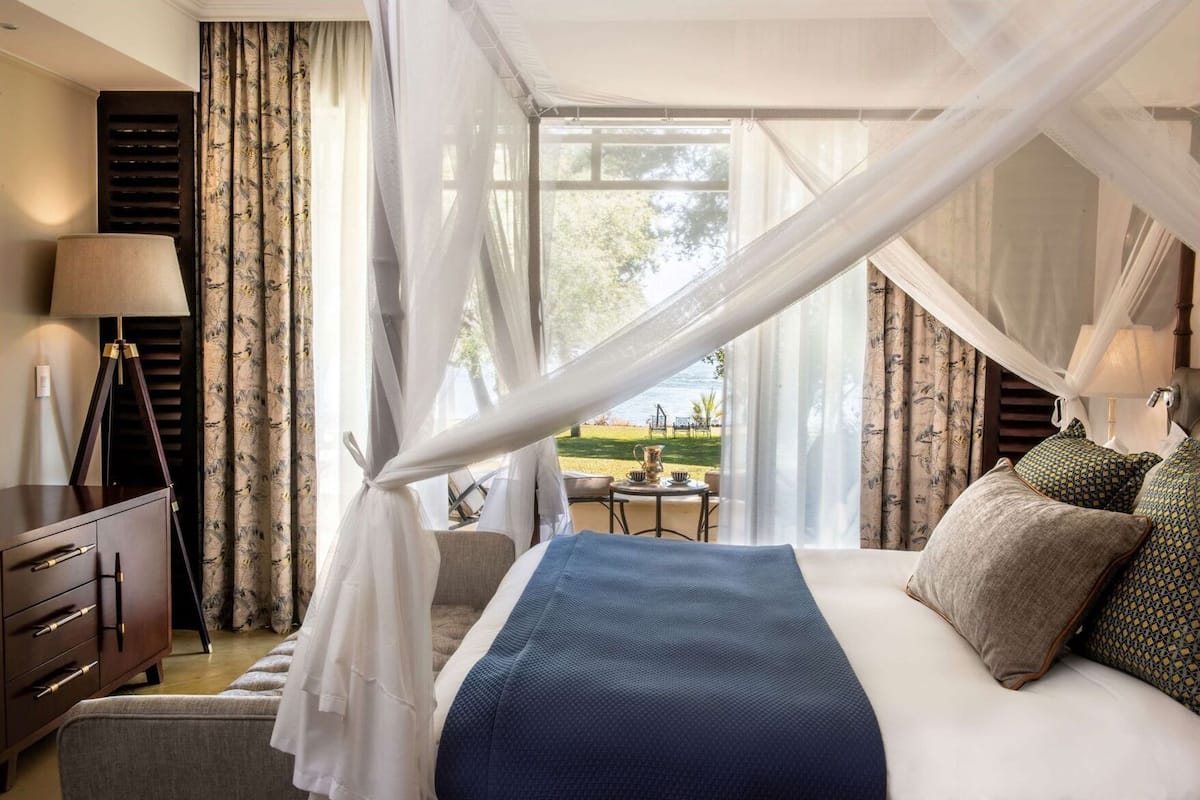 Ein Schlafzimmer mit Bett, Schreibtisch, Lampe und Blick ins Freie.