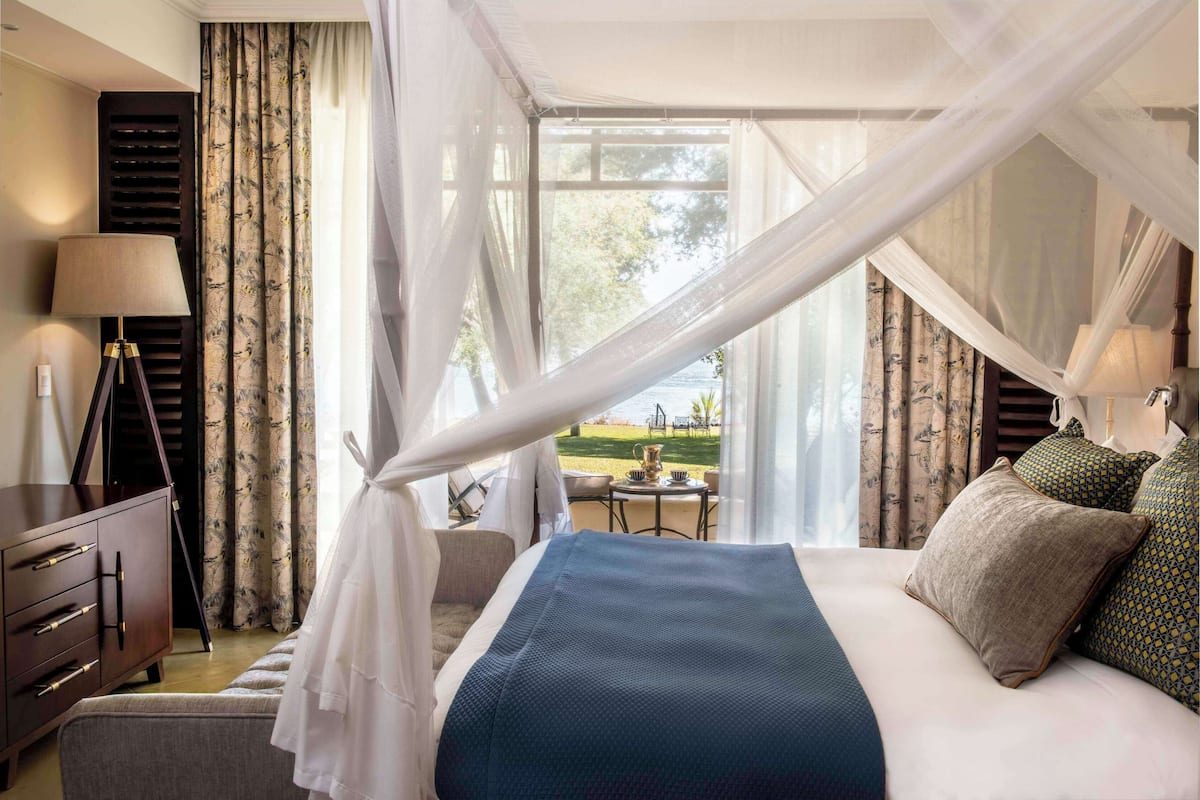Ein Hotelzimmer mit einem großen Bett, einem Schreibtisch, einem Sessel und Blick auf einen Garten.