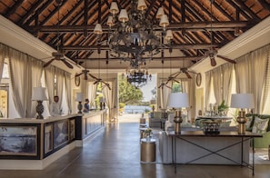 A hotel lobby with a reception desk, seating area, and a view of the outdoors. - Royal Livingstone Victoria Falls Zambia Hotel by Anantara (Livingstone)