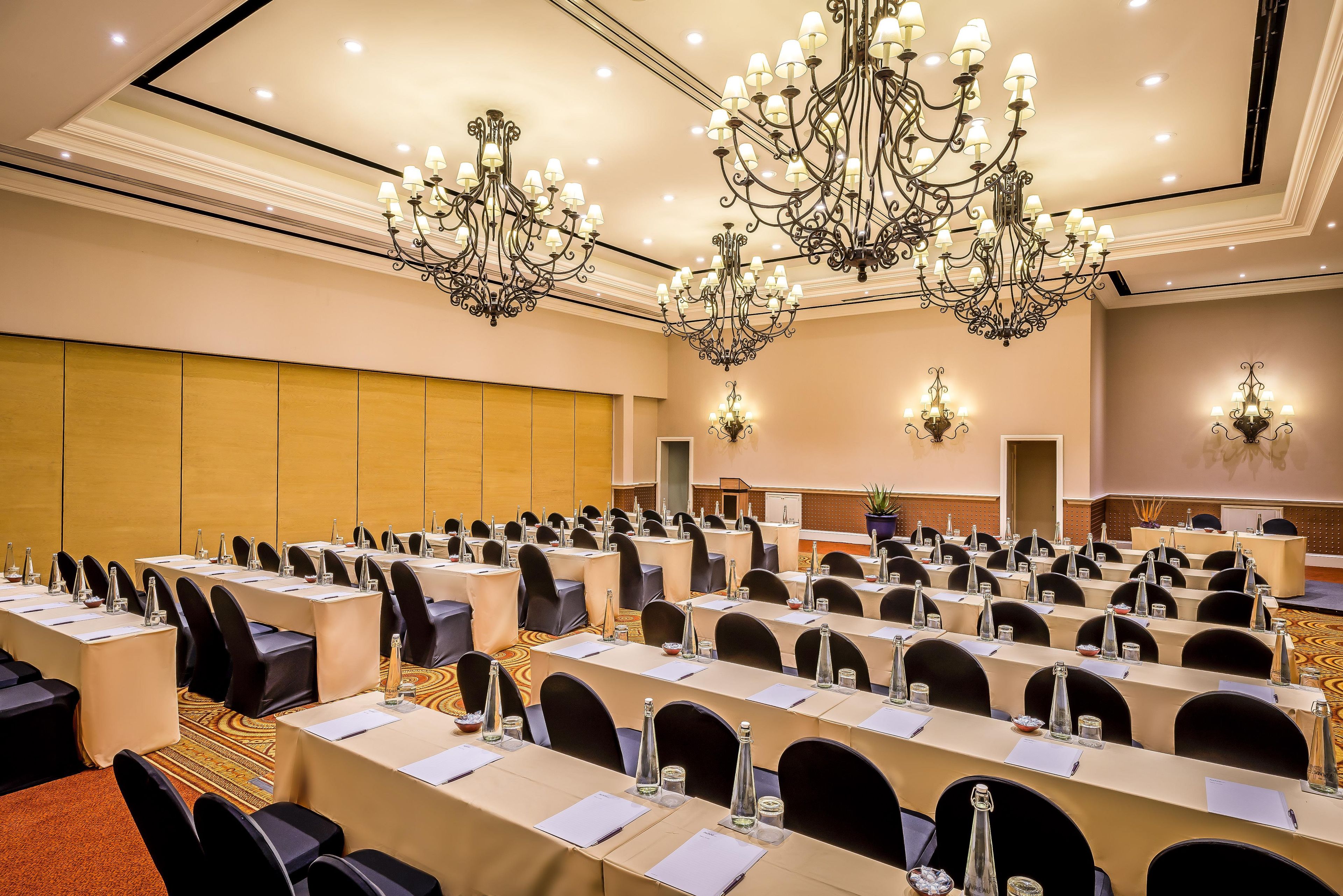 A conference room with multiple tables, chairs, and chandeliers.