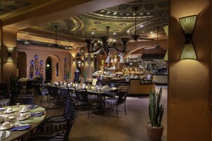 Een restaurant met meerdere tafels en stoelen, een bar en decoratieve elementen aan het plafond en de muren.