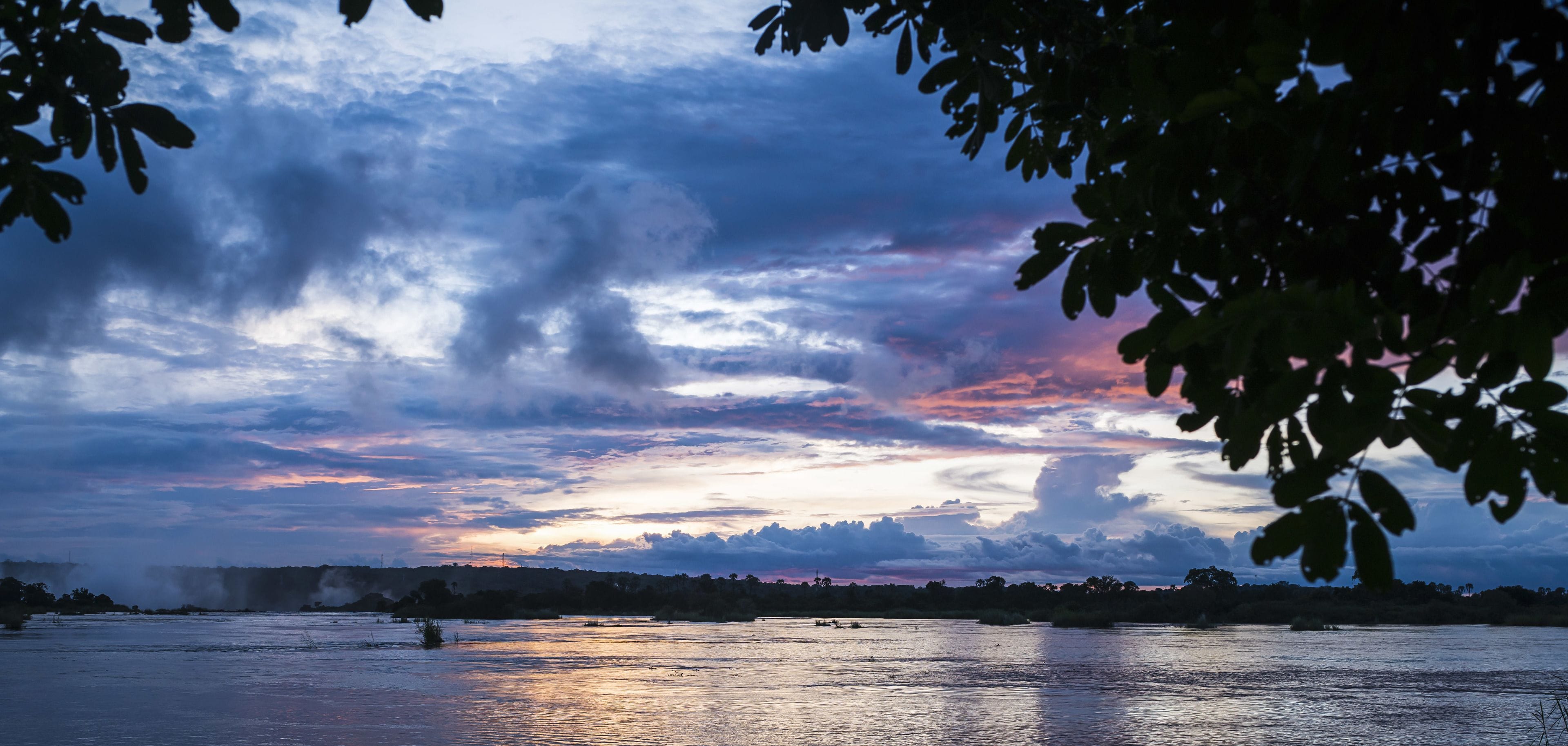 A river with a sunset sky, calm water, and a distant shoreline.