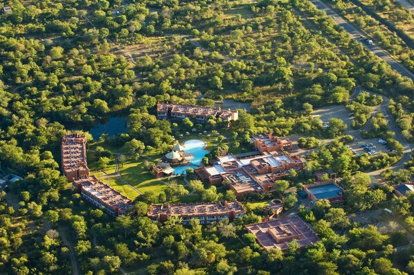 An aerial view of a resort with multiple buildings, a swimming pool, and surrounding greenery. - Avani Victoria Falls Resort (Livingstone)