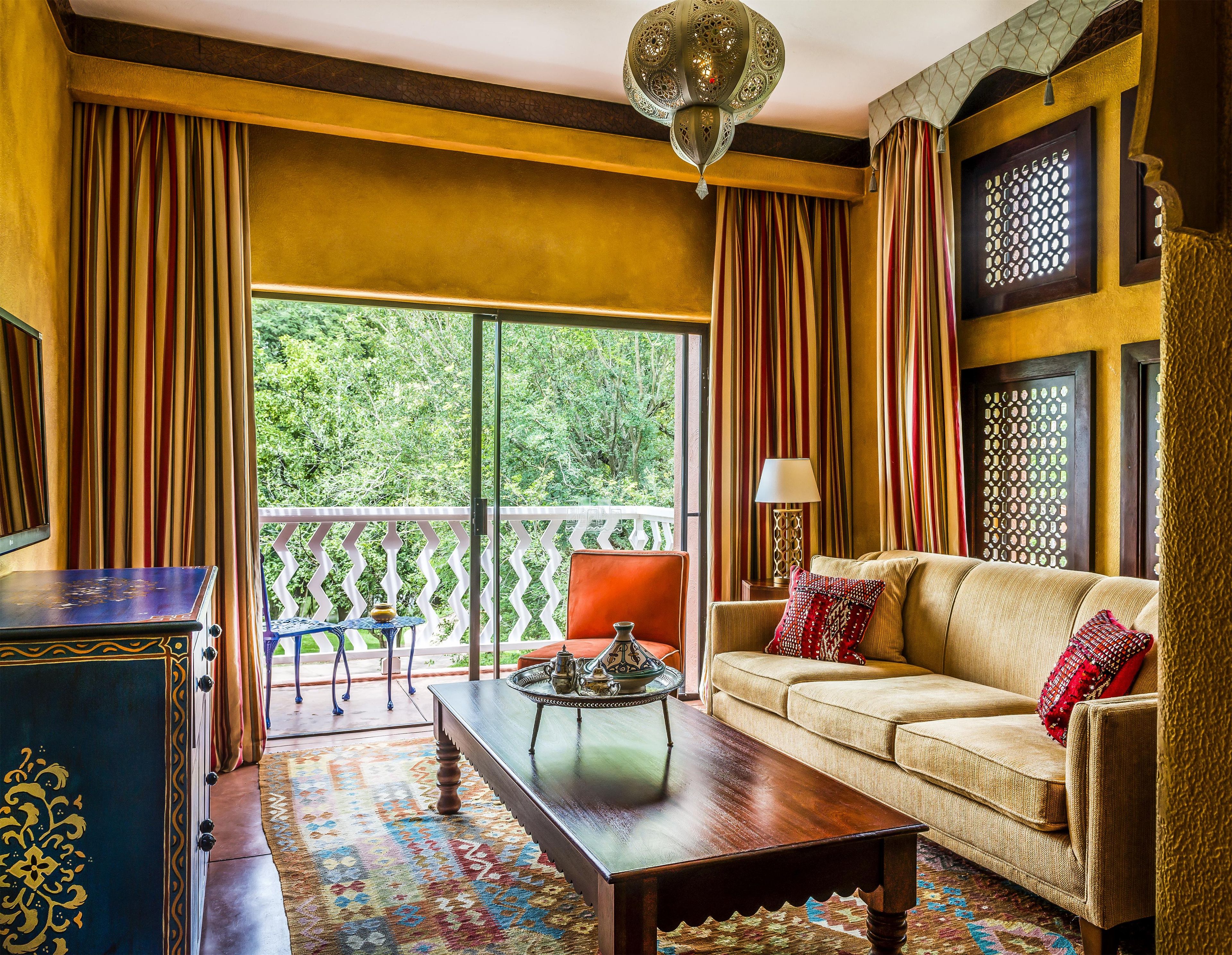 A room with a sofa, a table, a chair, and a view of greenery outside.
