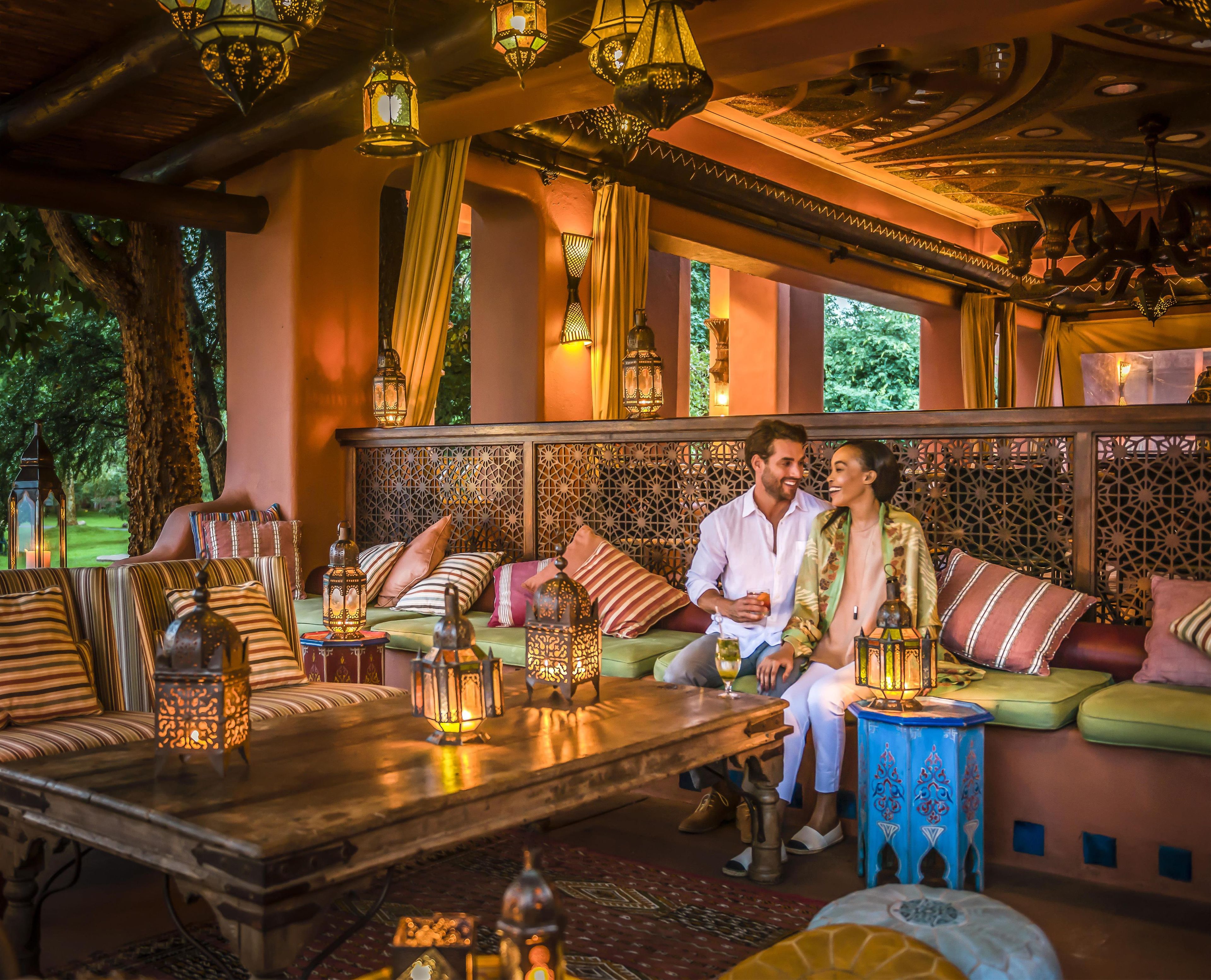 A cozy seating area with a sofa, cushions, and a table with lanterns.