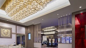 A spacious lobby with a geometric chandelier, a reception desk, and a red accent wall. - Caesars Southern Indiana Hotel & Casino - A Caesars Rewards Destination (Elizabeth)