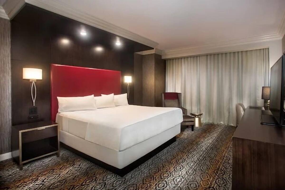 A hotel room with a large bed, a desk, a chair, and a television.