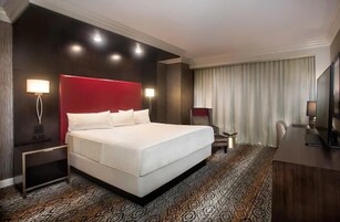 Una habitación de hotel con una cama grande, un escritorio, una silla y un televisor.