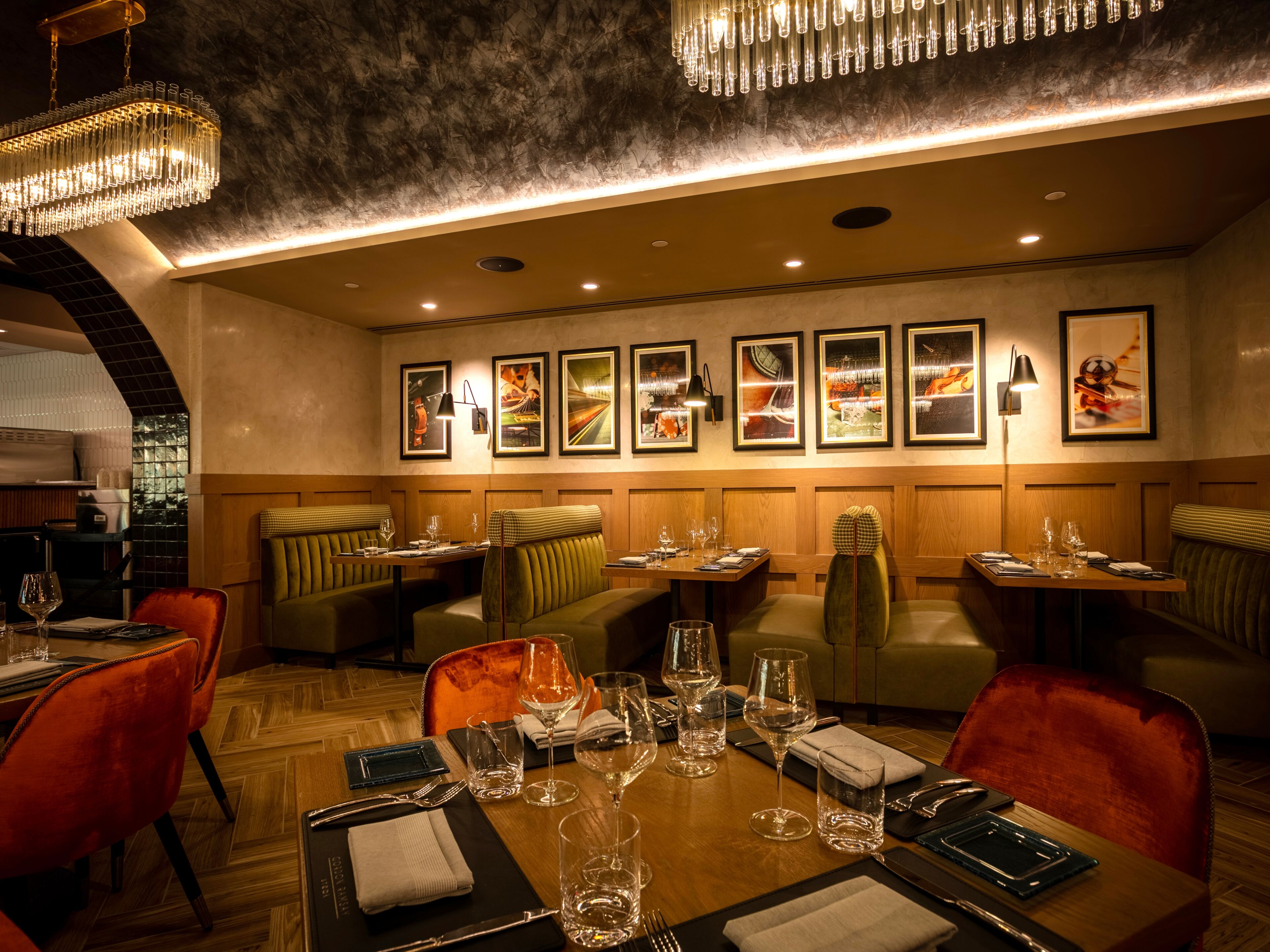 A restaurant with wooden booths, tables set with wine glasses, and framed pictures on the wall.